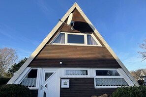 A triangular-shaped building with a sloped roof, a satellite dish, and a mailbox. - Holiday home in Damp with swimming pool (Damp)