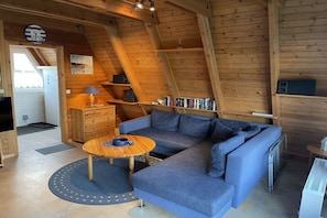 A cozy room with a blue sectional sofa, a wooden coffee table, and a bookshelf. - Holiday home in Damp with swimming pool (Damp)