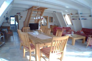 A spacious loft with a dining area, a red sofa, and a wooden staircase. - Holiday home in Damp with swimming pool (Damp)