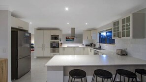 Une cuisine moderne dotée d’un îlot central, d’appareils électroménagers en acier inoxydable et offrant une vue sur la ville la nuit.