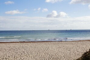 Een zandstrand met rustig water en een heldere lucht.