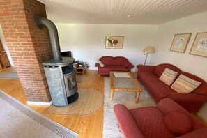A living room with a fireplace, red sofas, a coffee table, and a lamp. - Holiday home in Waabs with swimming pool (Waabs)