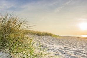 A sandy beach with grass in the foreground and a clear sky. - Holiday home with 2 bedrooms (Schwedeneck)