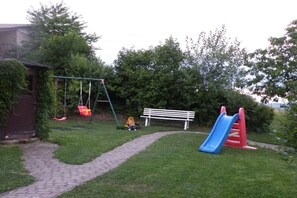 A playground with a swing set, slide, and bench. - Holiday home in Tann with swimming pool (Tann)