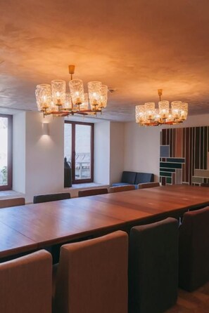 A conference room with a long table and multiple chairs, a chandelier, and a view of the outdoors. - Taboadella Casa Villae Relais & Chateaux (Silvã de Cima)