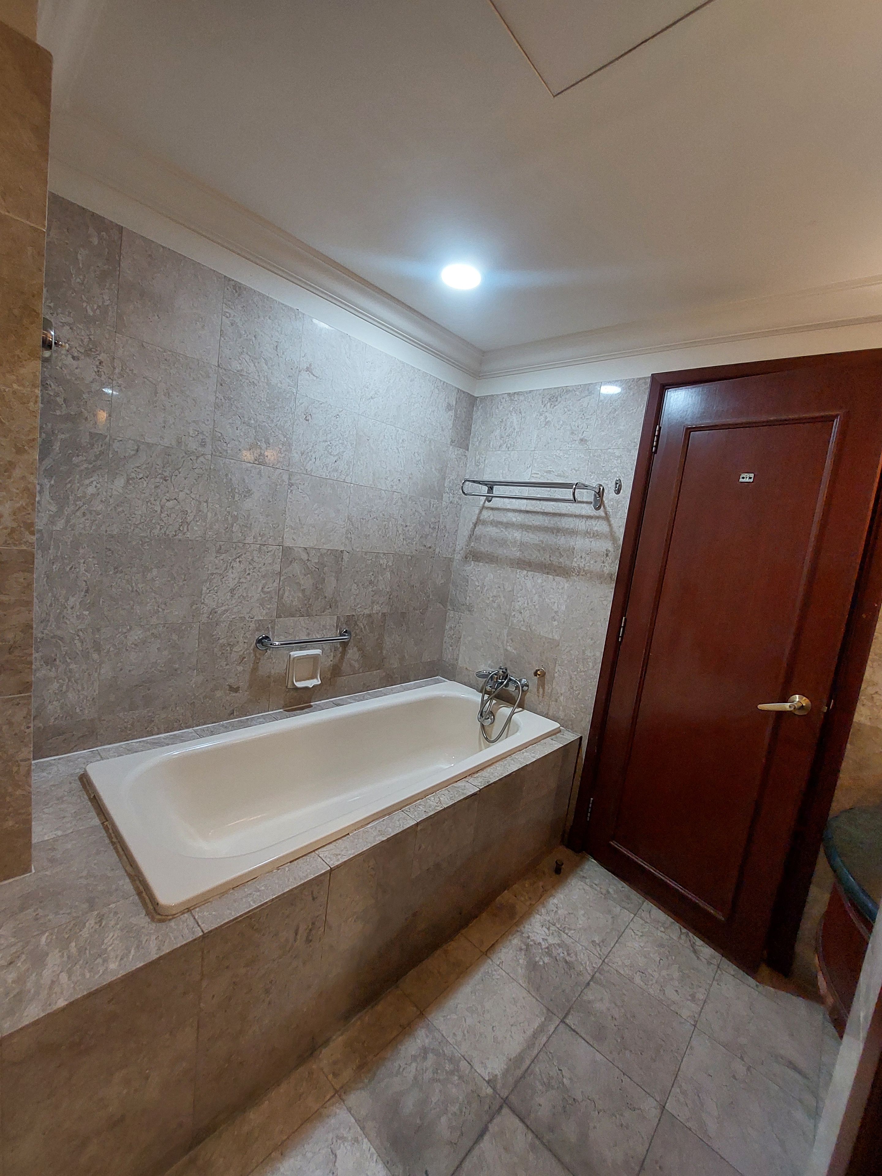 A bathroom with a bathtub, a towel rack, and a wooden door.