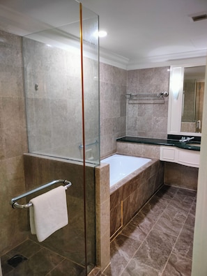 Un baño moderno con cabina de ducha de vidrio, bañera y tocador con espejo.