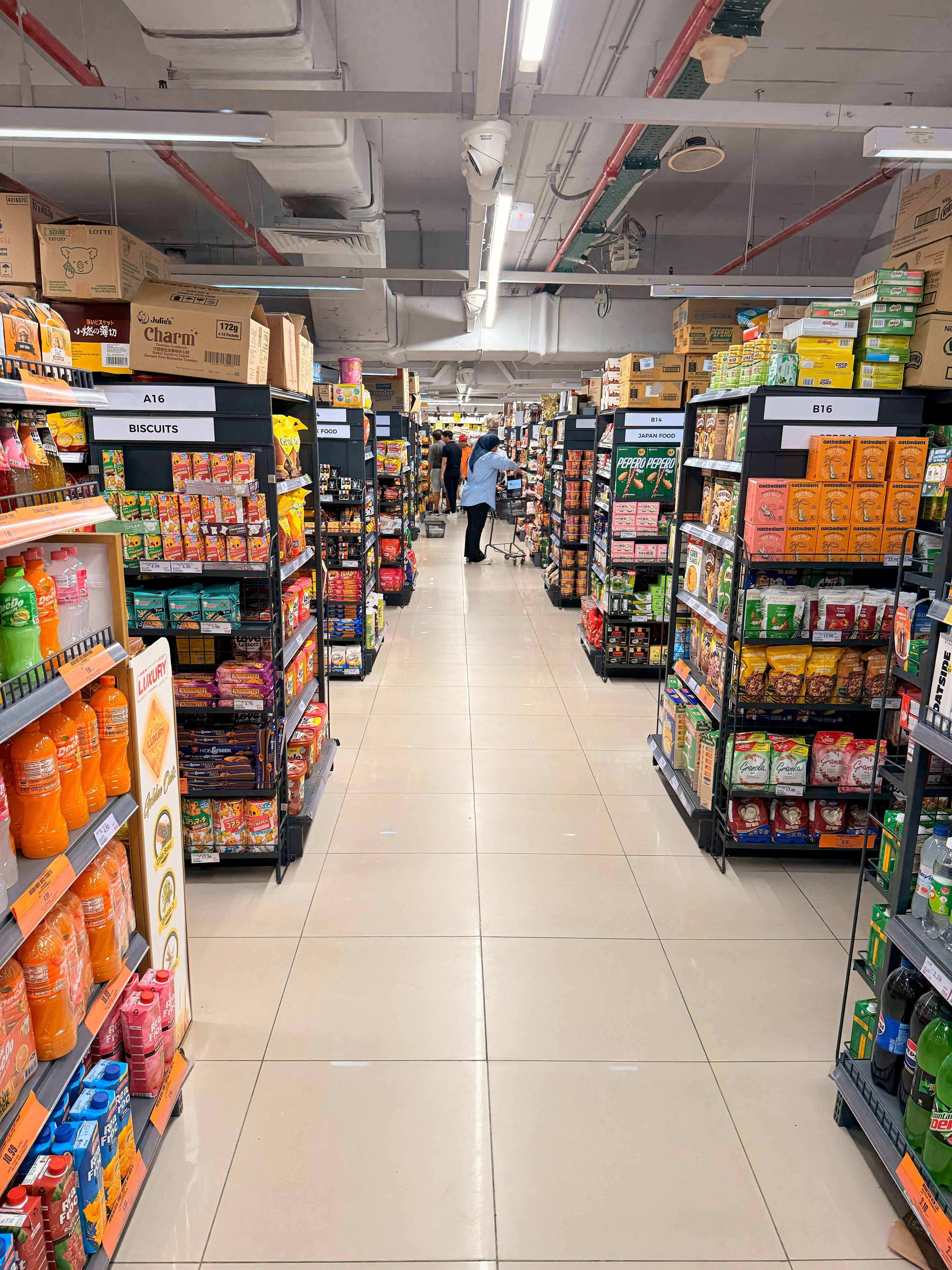 A supermarket aisle with various food products and a shopping cart.
