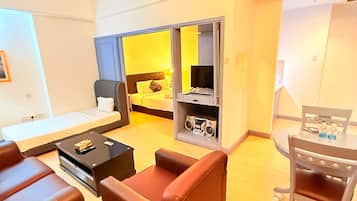 Una habitación de hotel moderna con cama, escritorio, silla, sofá y zona de comedor.