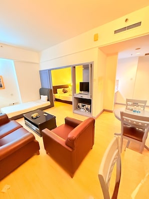 Una habitación de hotel moderna con cama, escritorio, silla, sofá y zona de comedor.