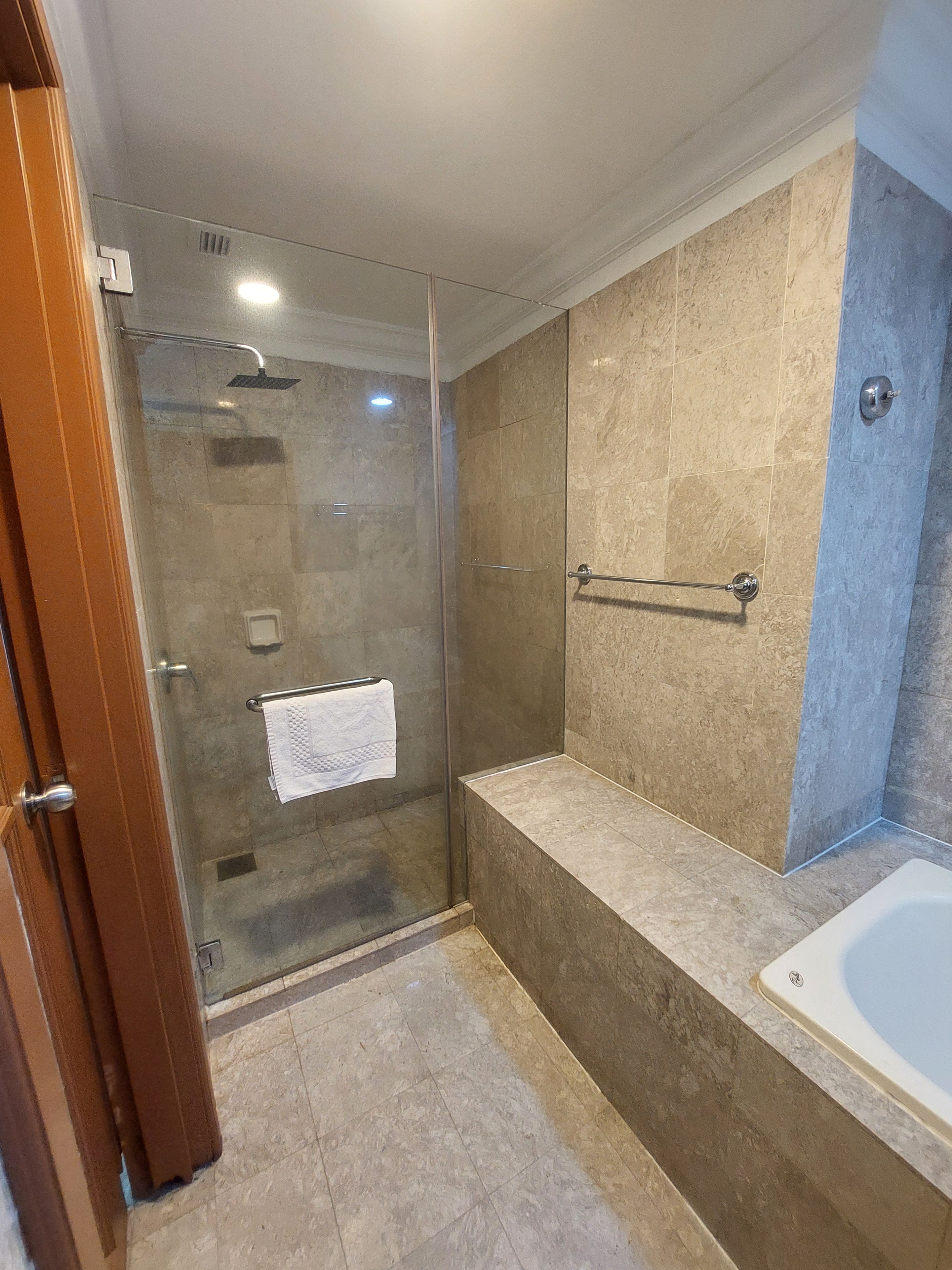 Une salle de bain avec une douche à parois de verre, une baignoire et un porte-serviettes.