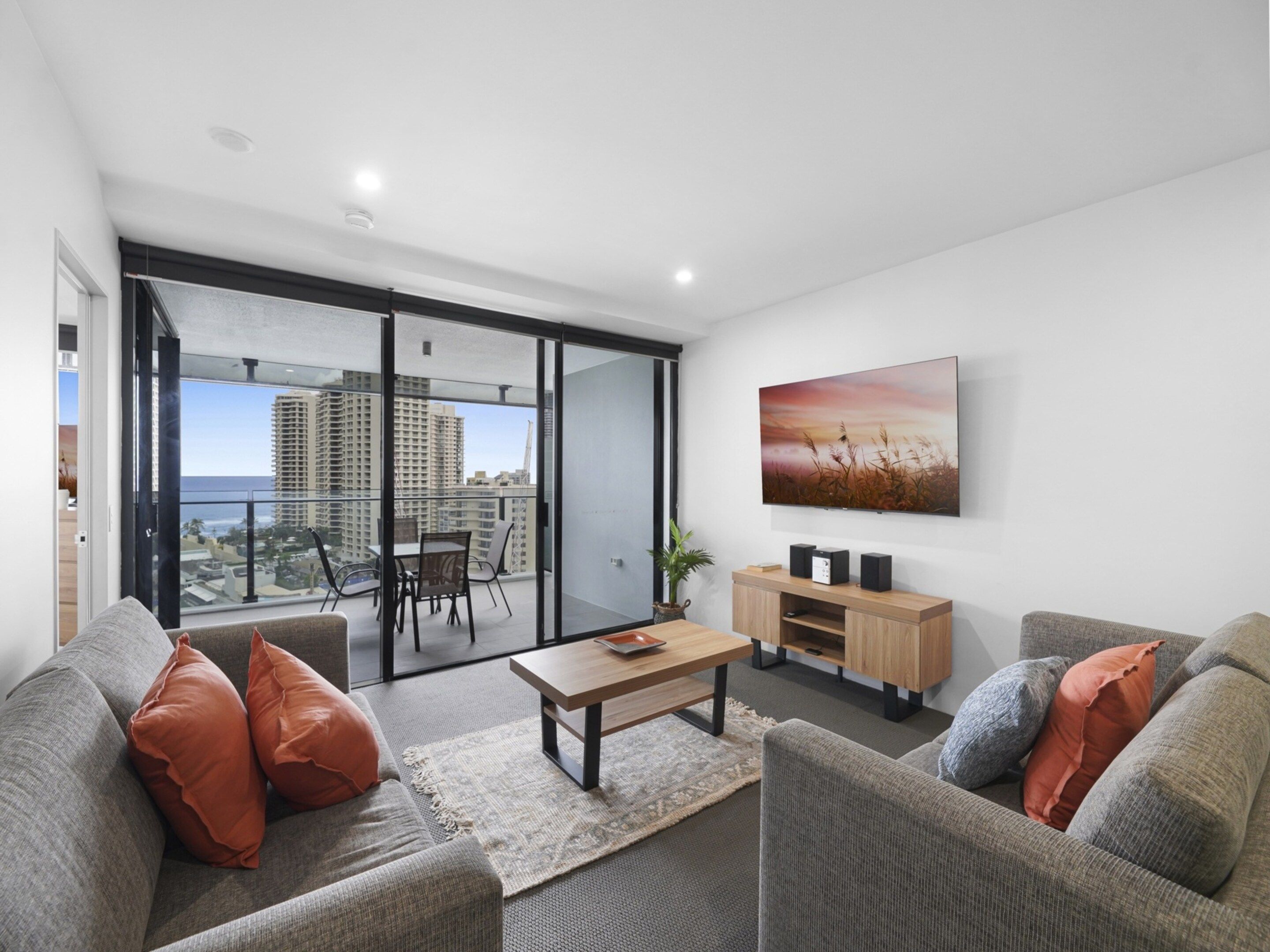 A modern living room with a sofa, coffee table, and a TV mounted on the wall.