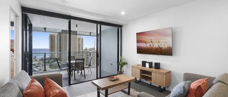 A modern living room with a sofa, coffee table, and a TV mounted on the wall.