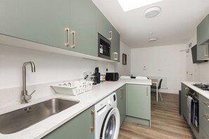 Een kleine keuken met een geïntegreerde wasmachine, een spoelbak en een magnetron.