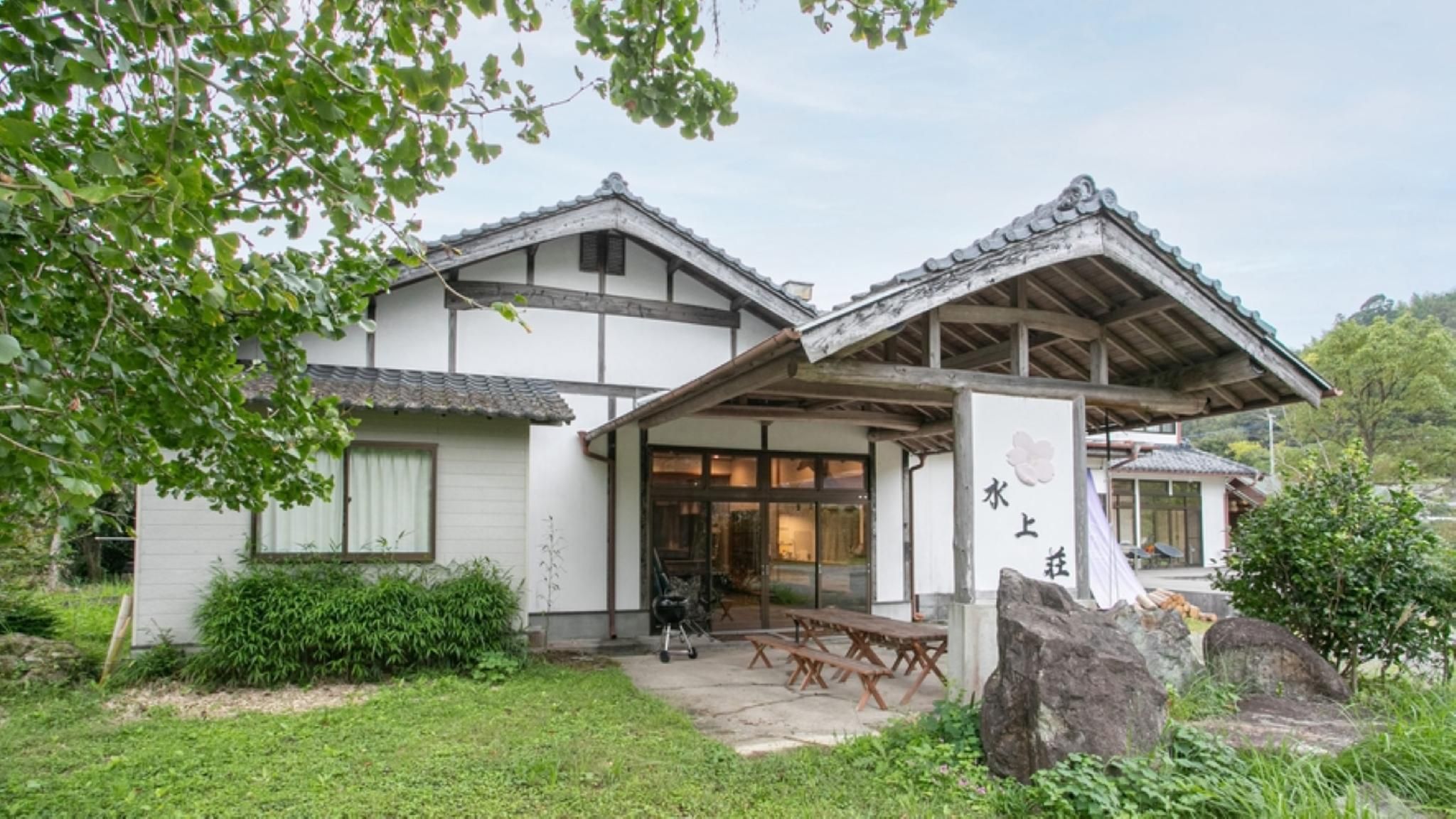 A traditional Japanese house with a tiled roof, a covered porch, and a stone pathway leading to the entrance.
