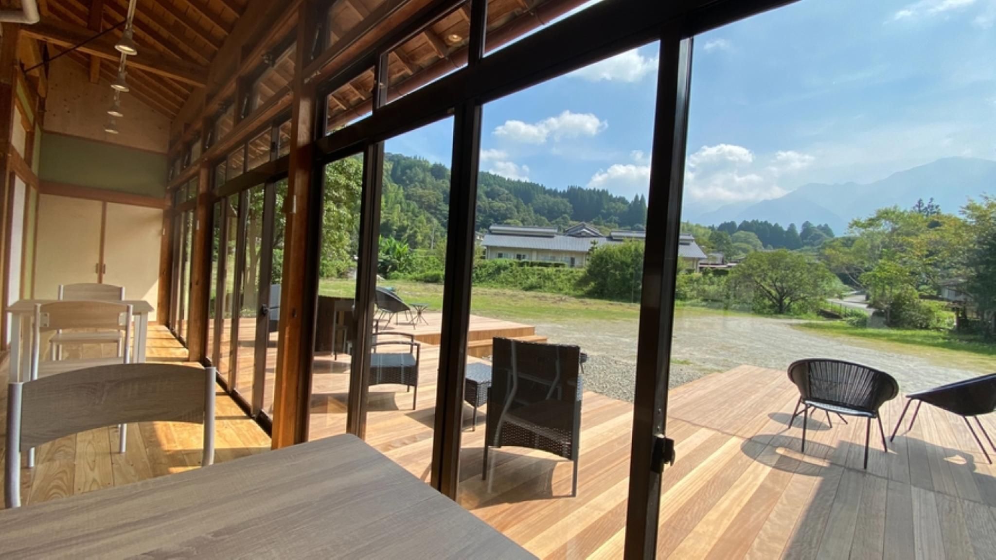A spacious room with large windows, wooden flooring, and a view of a mountainous landscape.