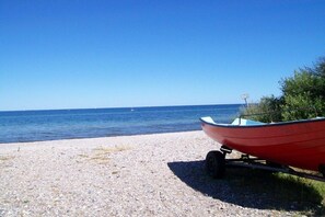 Ein Boot auf einem Trailer an einem Kiesstrand mit freiem Blick auf das Meer.