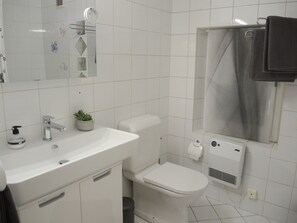 Een moderne badkamer met een wit wastafelmeubel, een toilet en een spiegel.