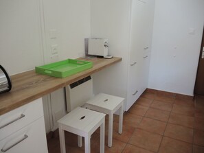 A kitchenette with a wooden countertop, a green tray, a white cabinet, and a white stool. - La Margarita by Interhome (Minusio)
