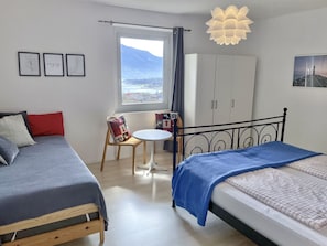 Een slaapkamer met twee bedden, een tafeltje, een kledingkast en een raam met uitzicht.