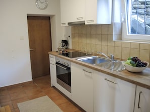 A kitchen with white cabinets, a stainless steel sink, and a built-in oven. - La Margarita by Interhome (Minusio)