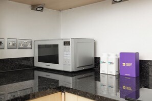 Une cuisine équipée d’un four à micro-ondes Panasonic, d’un plan de travail et d’un distributeur d’eau.