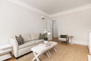 Un salon avec un canapé, une petite table, un banc et une porte à l’arrière-plan.