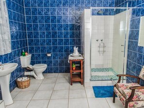 A bathroom with a toilet, sink, shower, and a chair. - Toeka Wedding & Function Venue (Lethabong)