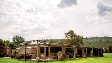 A rustic building with a covered porch and outdoor seating area, surrounded by a well-maintained lawn.