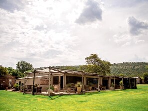 A rustic building with a covered porch and outdoor seating area, surrounded by a well-maintained lawn. - Toeka Wedding & Function Venue (Lethabong)