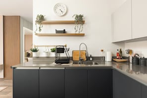Eine moderne Küche mit Kochinsel, Edelstahlgeräten und Holzböden mit Pflanzen.