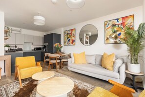 A modern living room with a sofa, chairs, a coffee table, and a dining area. - New! Stylish 1BR w/Balcony by Olympic Park (Greater London)