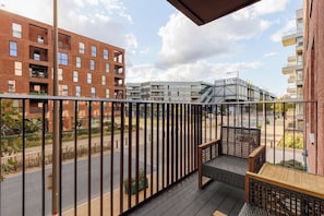 A balcony with a view of a modern building complex, featuring a mix of brick and glass facades. - New! Stylish 1BR w/Balcony by Olympic Park (Greater London)