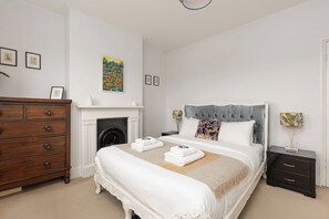 Ein Schlafzimmer mit Bett, Kommode, Nachttisch und Kamin.