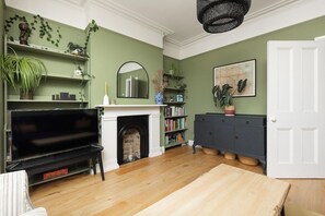 A living room with a fireplace, a television, and a bookshelf. - New! Characterful 3BR Home | Garden & Parking (Greater London)