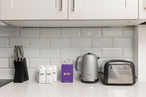 Eine Küchenarbeitsplatte mit Kaffeemaschine, Toaster, einem Messerset und Wasserflaschen.