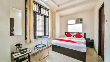 Una habitación de hotel con cama, escritorio, silla, ventana con cortinas y ventilador de techo.