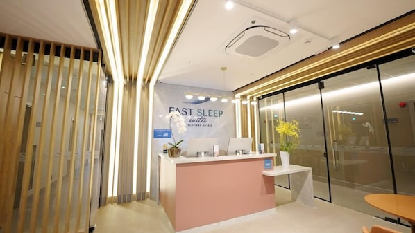 Un mostrador de recepción con un letrero que dice 'FAST SLEEP SUITES' y una planta en maceta.