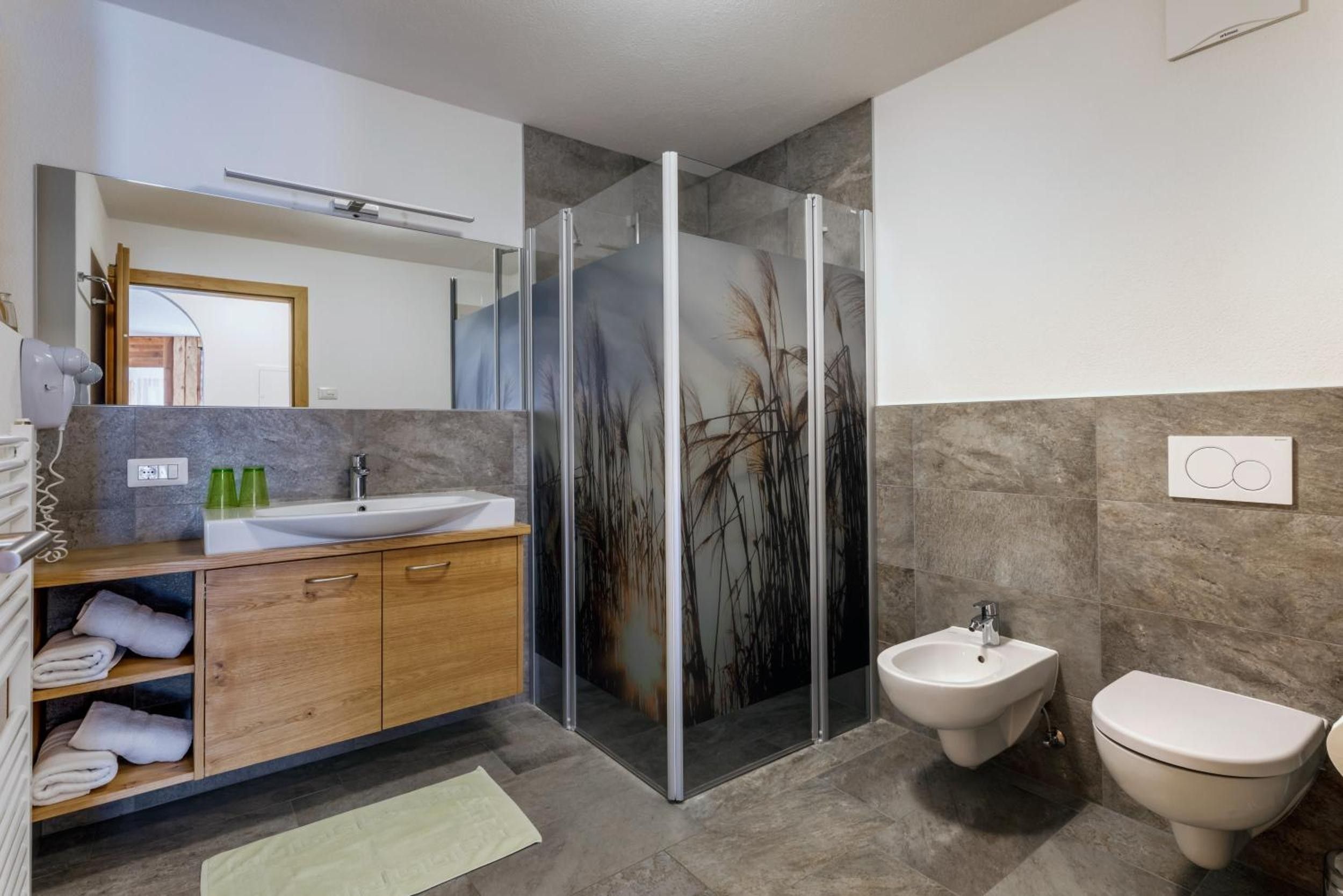 Ein modernes Badezimmer mit Duschkabine aus Glas, Waschbecken, Bidet und Toilette.