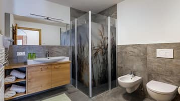 Une salle de bain moderne avec une douche à parois de verre, un lavabo, un bidet et des toilettes.