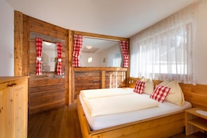 Una stanza in legno con un letto, uno specchio e tende.