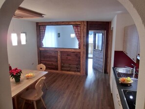 A dining area with a wooden table and chairs, a small potted plant, and a view through an open door to a balcony. - Apartment 'Zangerlehof  Rasass' with Mountain View, Shared Garden and Wi-Fi (Slingia)