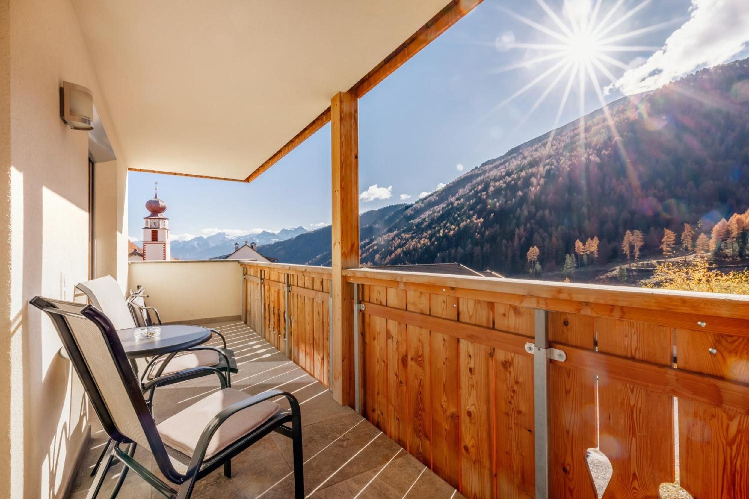 Un balcone con ringhiera in legno, un tavolo e due sedie.