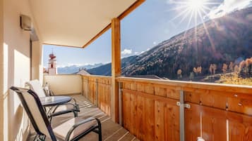 Un balcone con ringhiera in legno, un tavolo e due sedie.