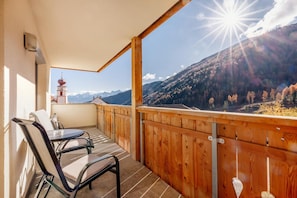 Un balcone con ringhiera in legno, un tavolo e due sedie.