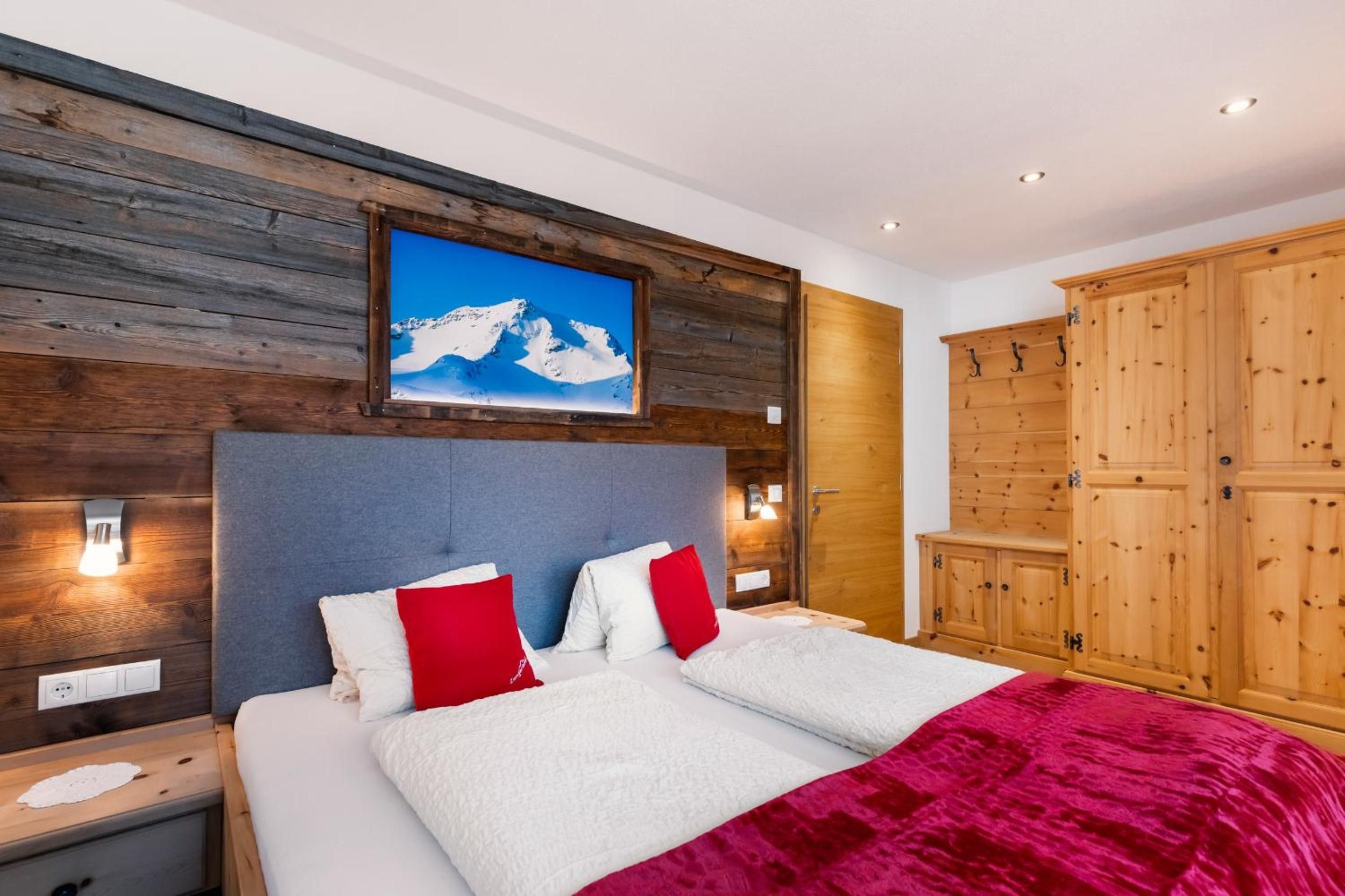 Una camera da letto con un letto, una testiera in legno, un quadro raffigurante una montagna e un armadio.