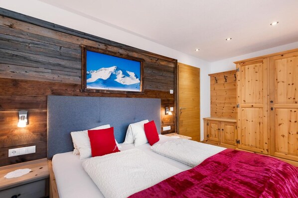 Una camera da letto con un letto, una testiera in legno, un quadro raffigurante una montagna e un armadio.