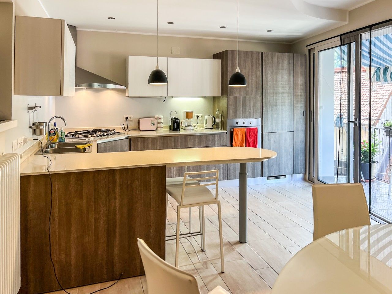Una cocina moderna con una isla central, iluminación colgante y vistas al exterior.
