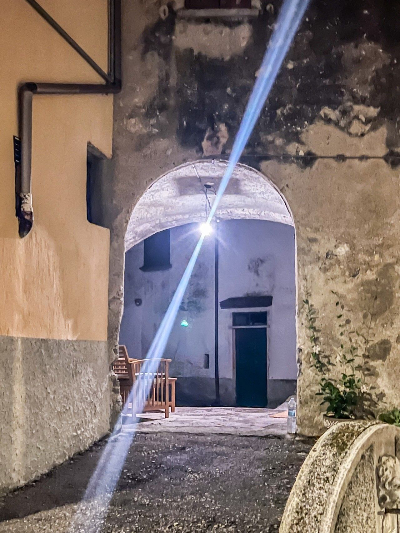 An arched doorway leading to a building with a small outdoor seating area.