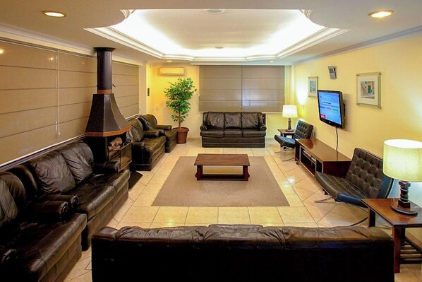 A living room with a fireplace, leather sofas, a coffee table, and a television.